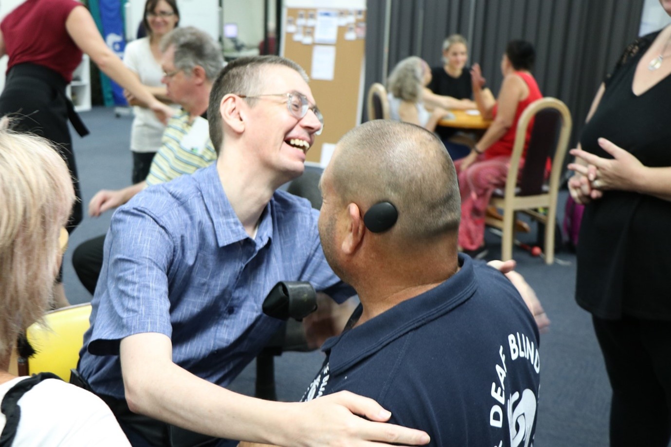 A photo of two Deafblind members smiling and hugging