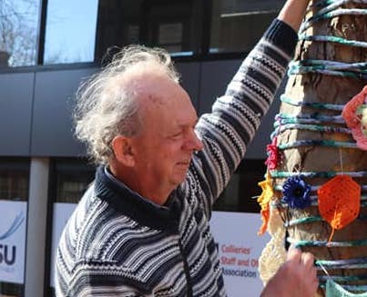 Stephen standing next to tree that has been yarn bombed