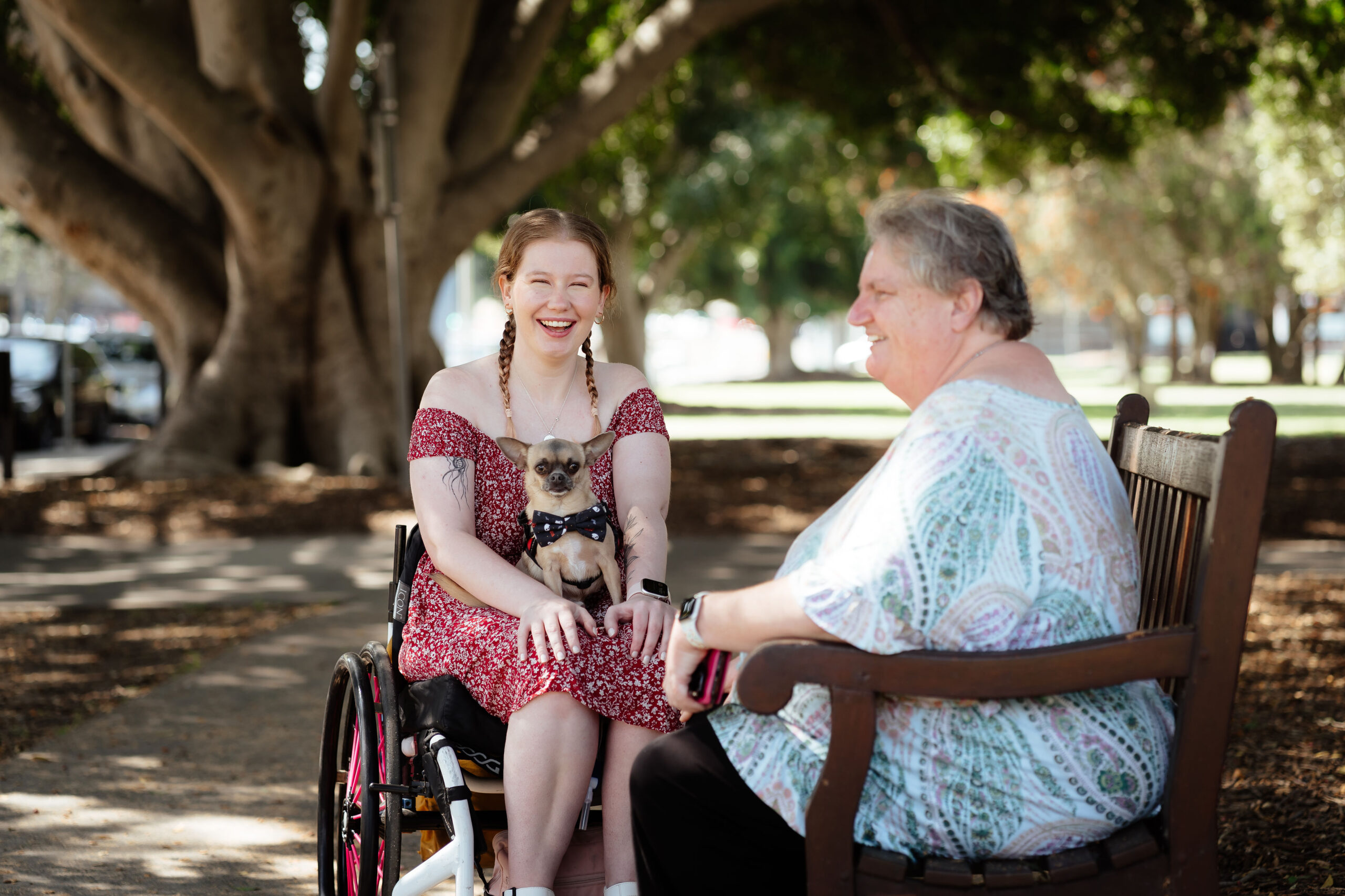 Image description: Two peers sitting together in a shady park