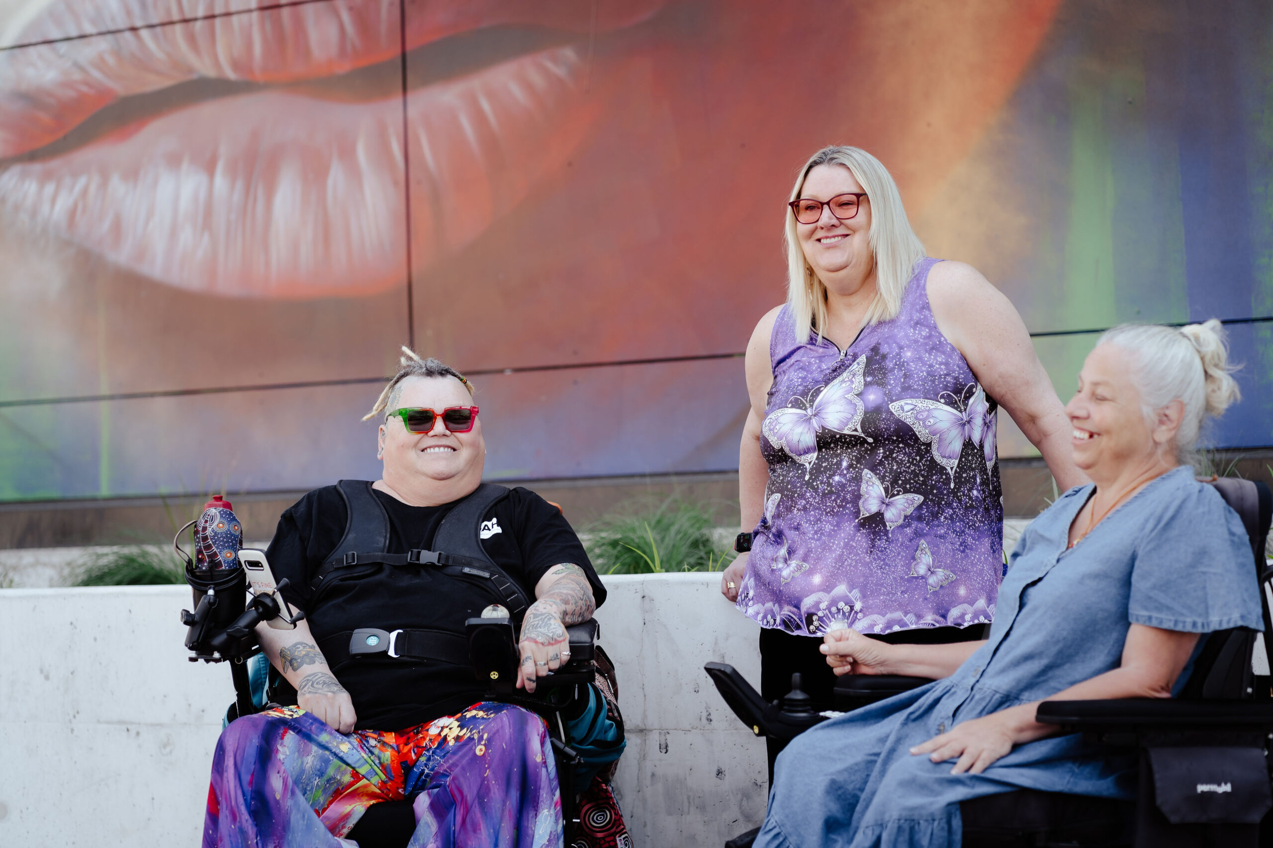 Image description: Three CDAH peers infront of outdoor mural