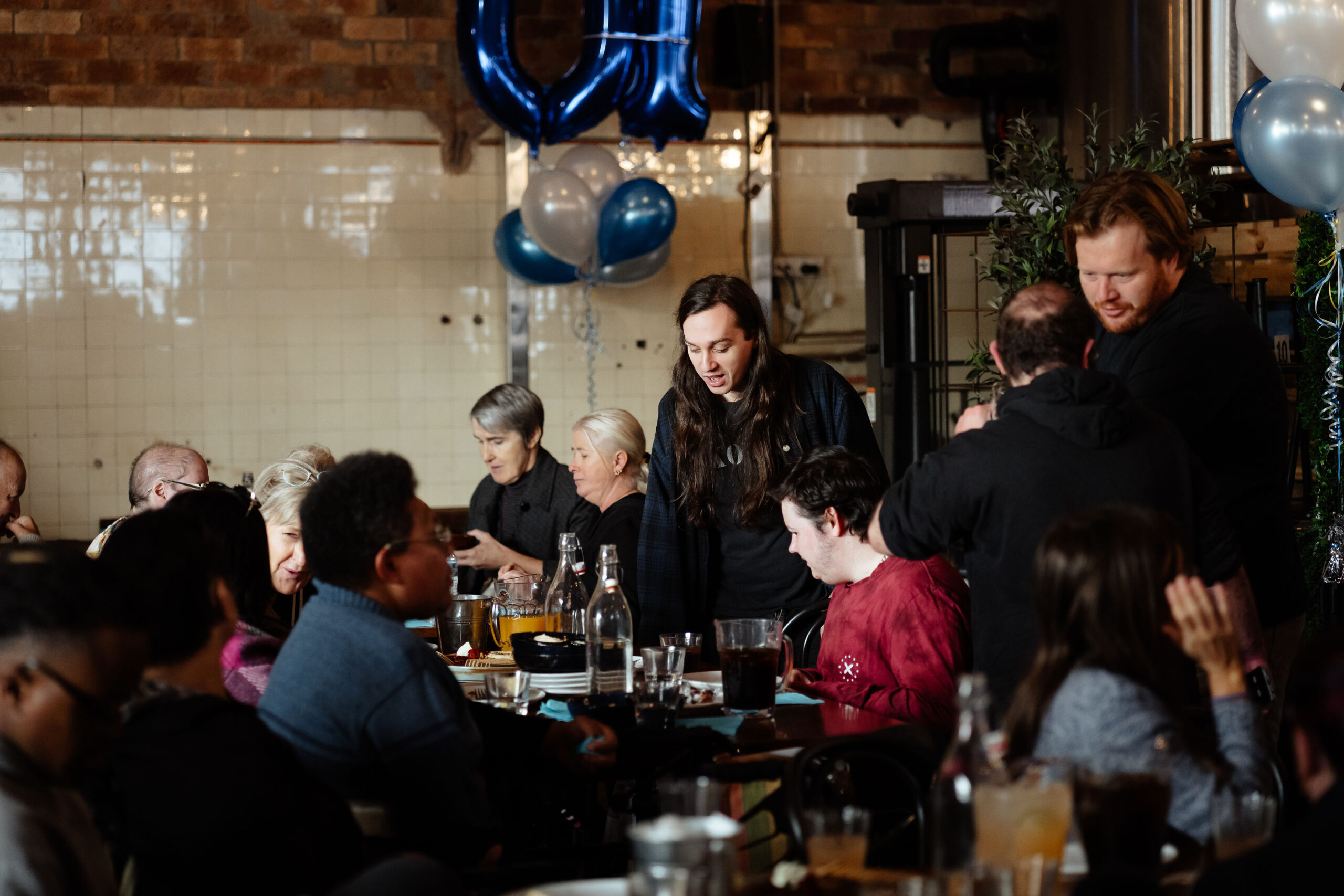 Image description: a group of CDAH peers talking amongst themselves below some blue balloons