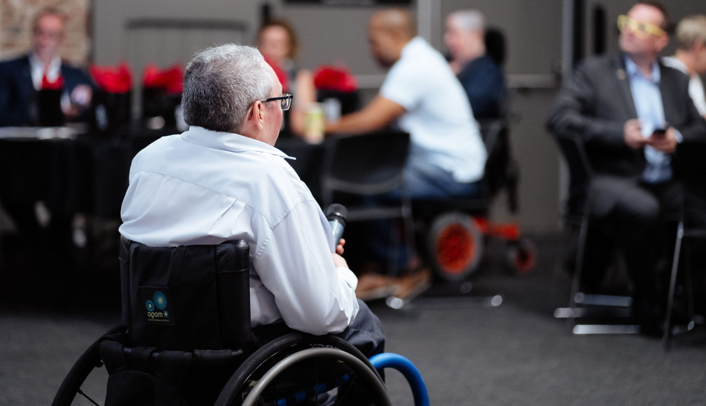 Image description: David Belcher holding a microphone in front of audience