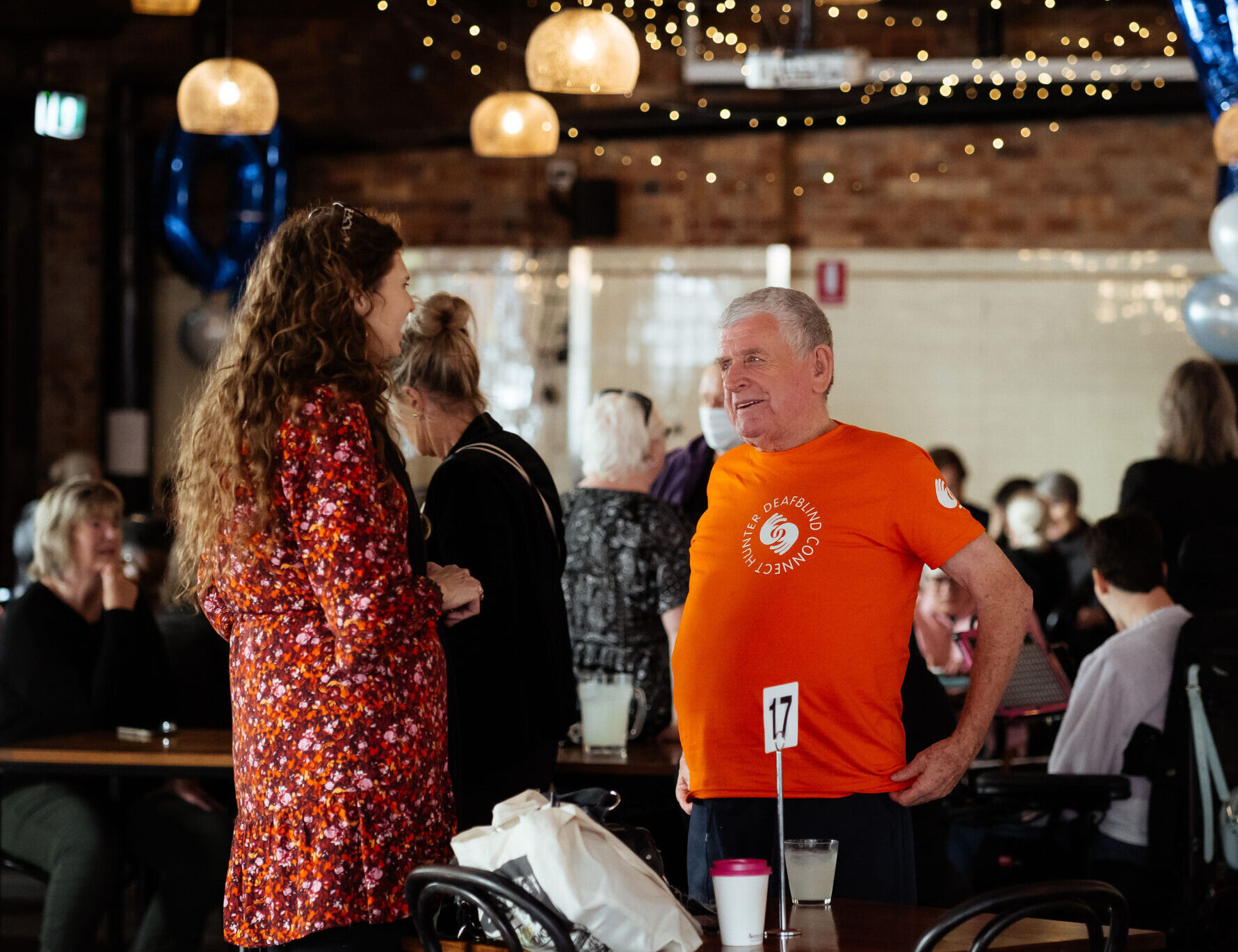 Image description: Woman speaking with Hunter Deafblind peer indoors