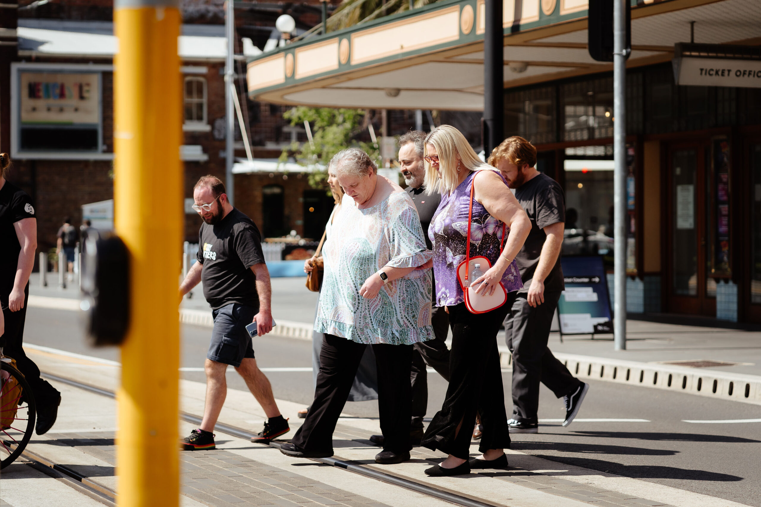 Image description: CDAH peers crossing the newcastle tramline on a sunny day