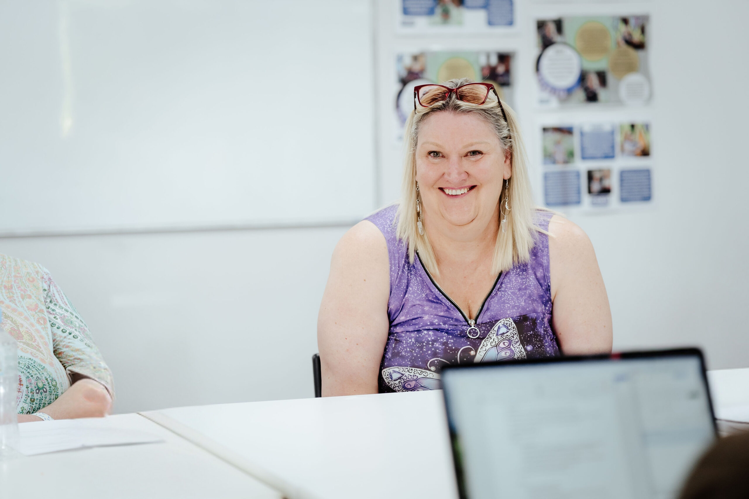 Image description: CDAH peer smiling around indoor table